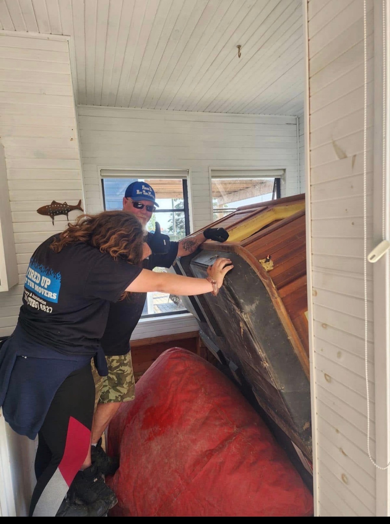 Team maneuvering a hot tub through tight space
