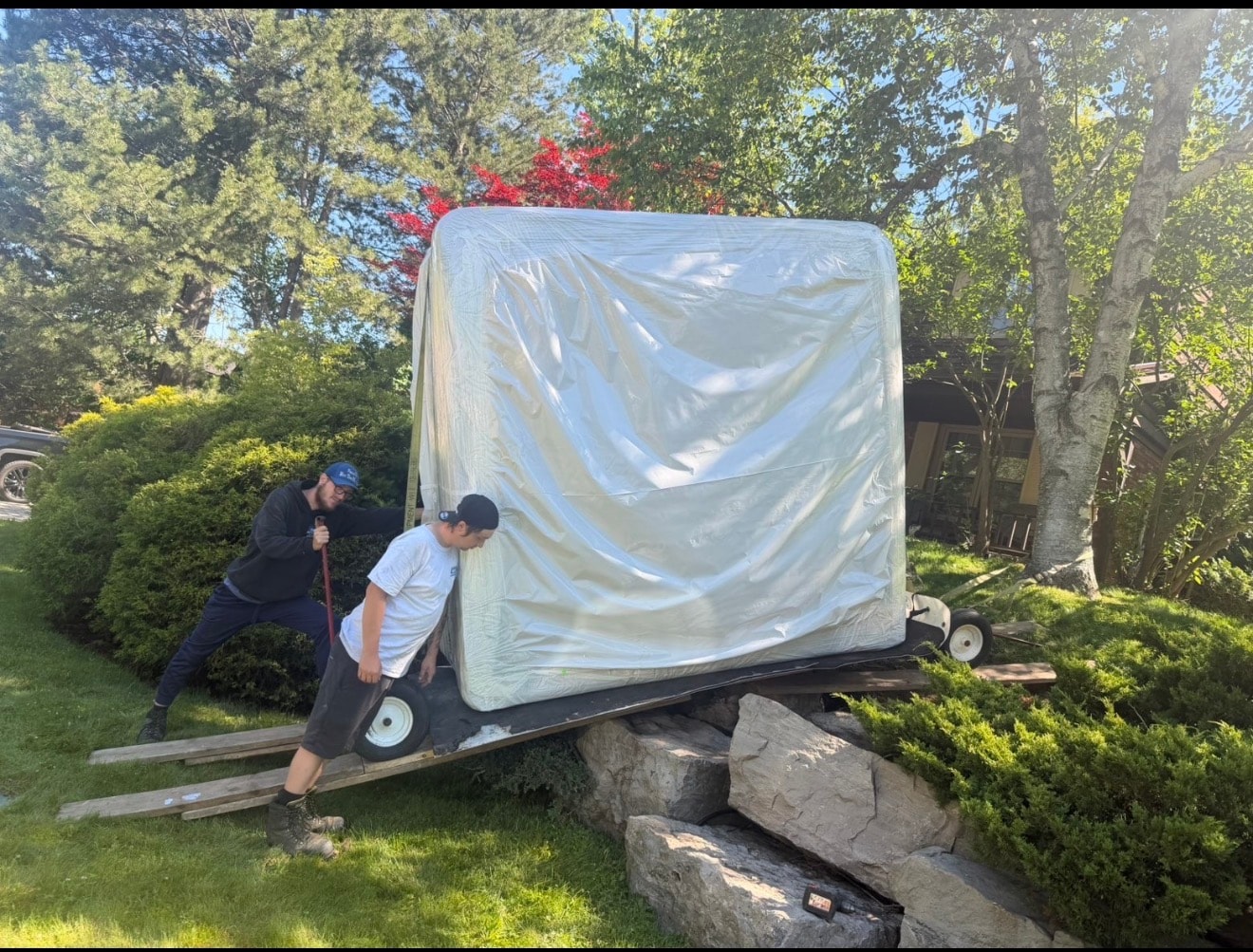 Team pushing wrapped hot tub on dolly