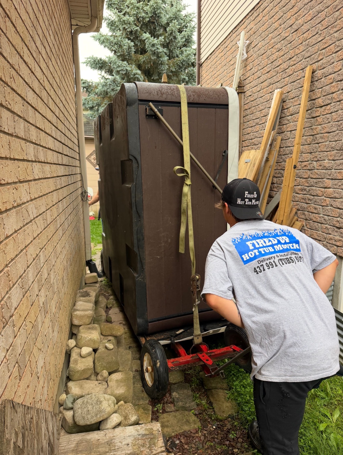 Hot tub being moved through narrow side yard